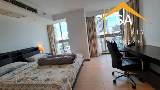 Spacious bedroom with double bed, desk, and city view