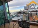 Balcony with a table and chairs overlooking city buildings and partial water view