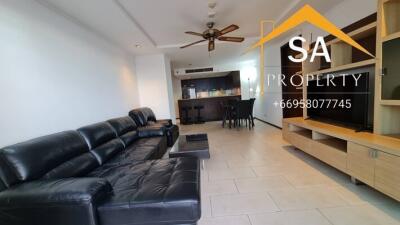 Spacious living room with black leather sofa and open kitchen