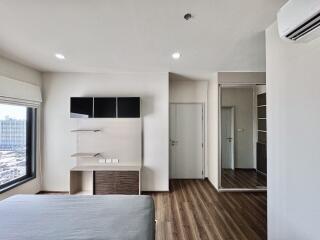 Modern bedroom with large window, shelves, and wooden flooring