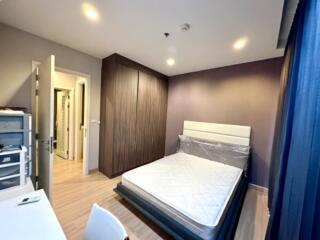 Modern bedroom with wooden flooring, bed, and closet