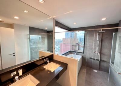 Modern bathroom with large mirrors, double sinks, shower, and city view