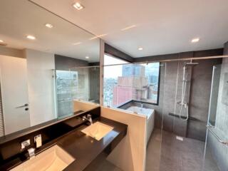 Modern bathroom with large mirrors, double sinks, shower, and city view