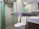 Modern bathroom with glass shower, toilet, and sink