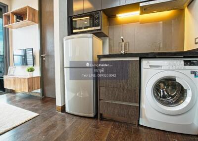 Modern kitchen area with appliances including a refrigerator, washing machine, and microwave