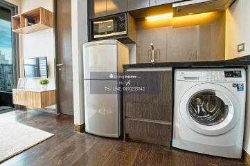 Modern kitchen area with appliances including a refrigerator, washing machine, and microwave