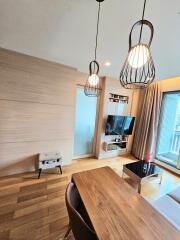 Modern living room with wooden flooring, hanging lights, and a large window