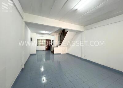 Open area with blue tiled floor, white walls, and a staircase