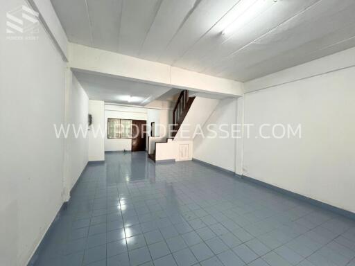 Open area with blue tiled floor, white walls, and a staircase