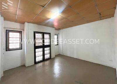 Empty room with tiled ceiling and windows covered with bars