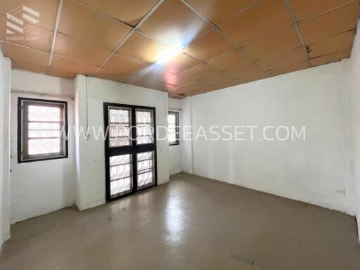 Empty room with tiled ceiling and windows covered with bars