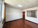 Empty bedroom with wooden floor and windows