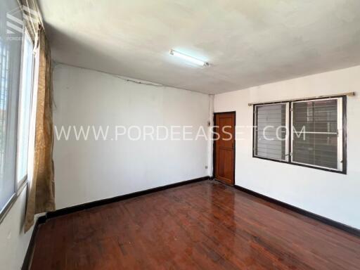 Empty bedroom with wooden floor and windows