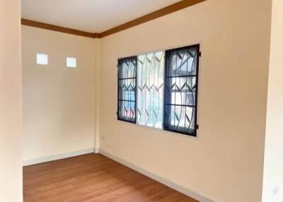 Empty bedroom with wooden floor and large window with security bars