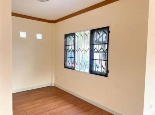 Empty bedroom with wooden floor and large window with security bars