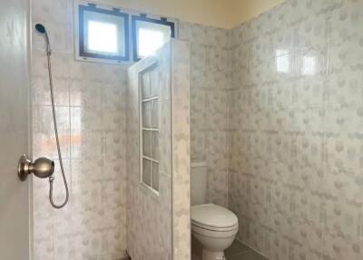 Bathroom with tiled walls, shower, and toilet