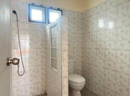 Bathroom with tiled walls, shower, and toilet