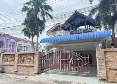 Front view of a two-story house with a gated entrance and a blue awning