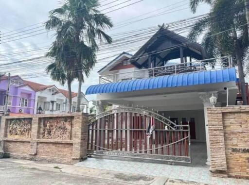 Front view of a two-story house with a gated entrance and a blue awning