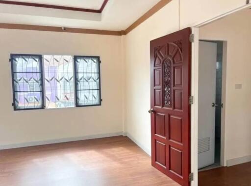 Empty bedroom with wooden door and windows with grills