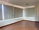 Spacious room with large windows and vertical blinds