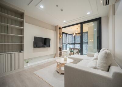 Modern living room with couch, TV, and large windows