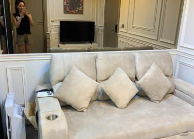 Living room with light-beige couch, wall-mounted TV, and air conditioning unit