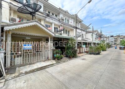 Exterior view of a multi-storey residential building with satellite dishes and potted plants.