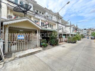 Exterior view of a multi-storey residential building with satellite dishes and potted plants.