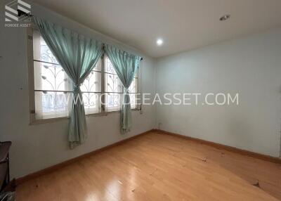 Empty bedroom with wooden flooring and large window with curtains