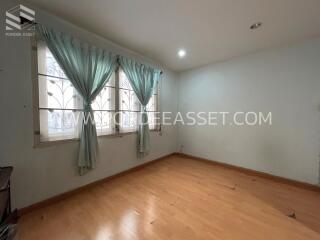 Empty bedroom with wooden flooring and large window with curtains