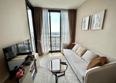 Modern living room with large windows, a sofa, a coffee table, and a TV.