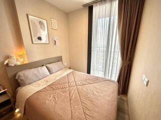 Cozy bedroom with a double bed, framed artwork, and a large window with curtains