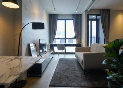 Modern living room with a desk by the window, sofa, TV, and potted plant