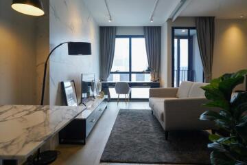 Modern living room with a desk by the window, sofa, TV, and potted plant