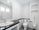 Modern bathroom with sink, toilet, urinal, and built-in shelves