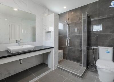 Modern bathroom with a large mirror, sink, toilet, and walk-in shower