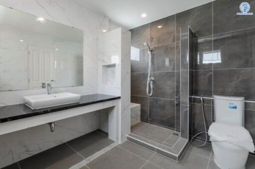 Modern bathroom with a large mirror, sink, toilet, and walk-in shower