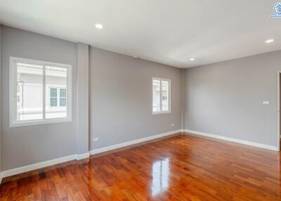 Bright, empty living room with wooden floors and large windows