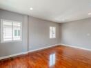 Bright, empty living room with wooden floors and large windows