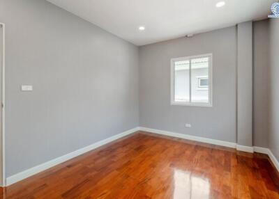 A bright empty bedroom with wooden flooring