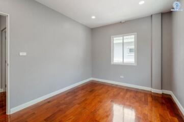 A bright empty bedroom with wooden flooring