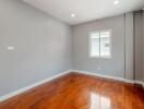 A bright empty bedroom with wooden flooring