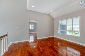 Spacious living room with hardwood floors and large window.