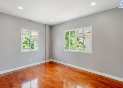 Spacious bedroom with wooden flooring and large windows