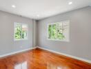 Spacious bedroom with wooden flooring and large windows