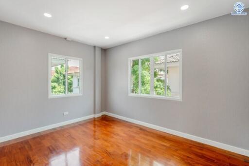 Spacious bedroom with wooden flooring and large windows