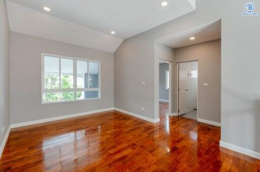 Spacious bedroom with wooden floors and large window