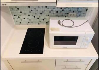 Modern kitchen with stovetop, microwave, and tiled backsplash