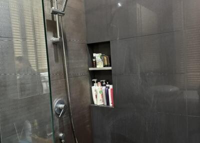 Modern shower area with black tiles and built-in shelves